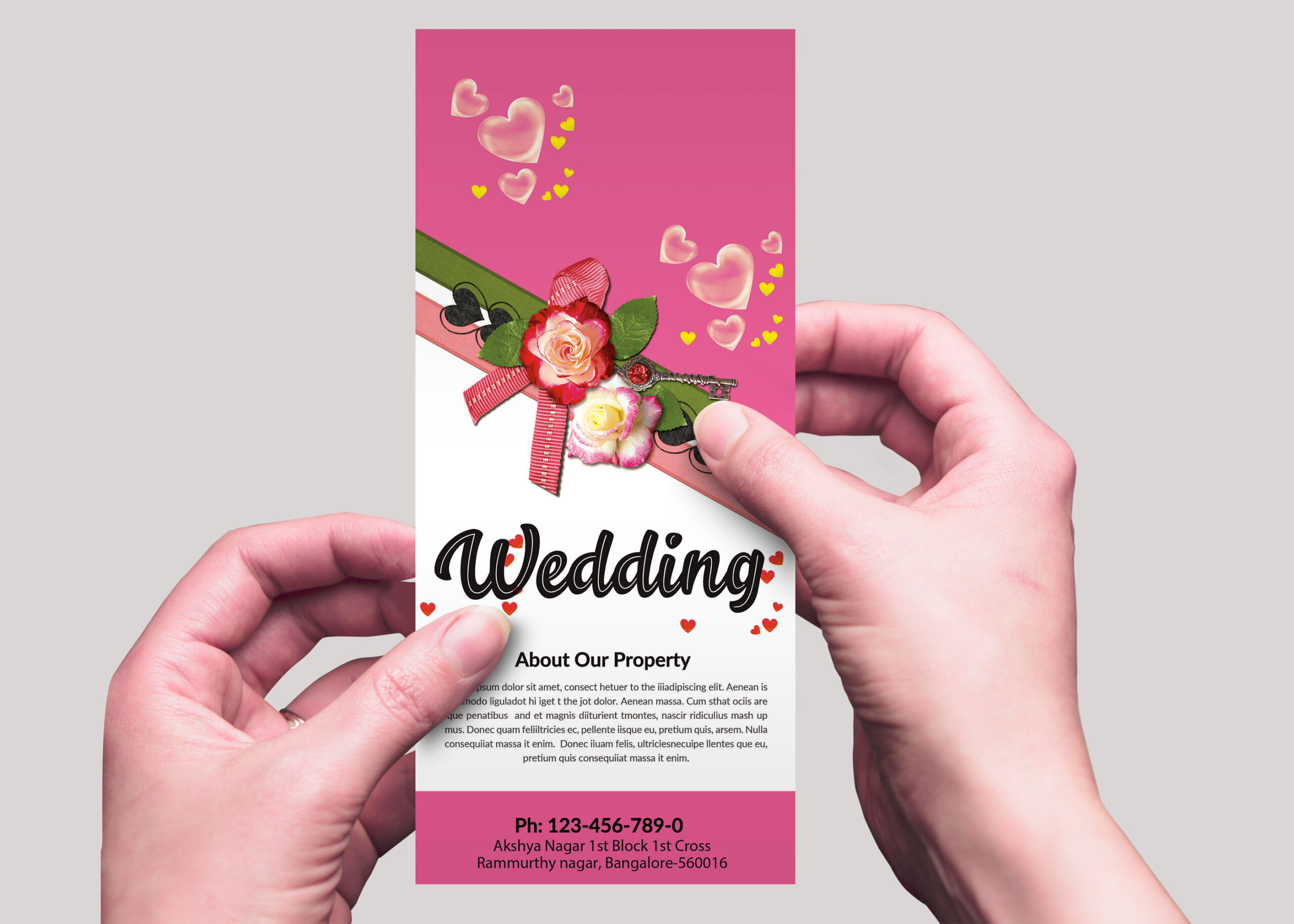 A person holds a pink wedding brochure adorned with flowers, hearts, and contact details for a wedding venue.